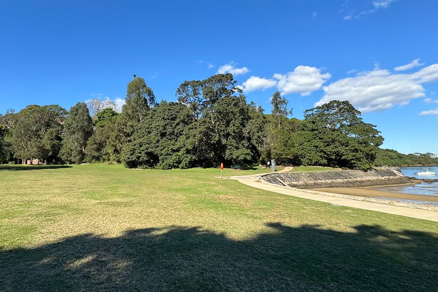Expansive grassy area at Sirius Cove Reserve dog park in Mosman with beach access and leafy surroundings